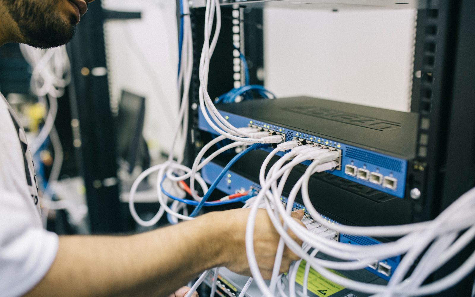 Network engineer installing and organizing physical connectivity in enterprise server infrastructure.