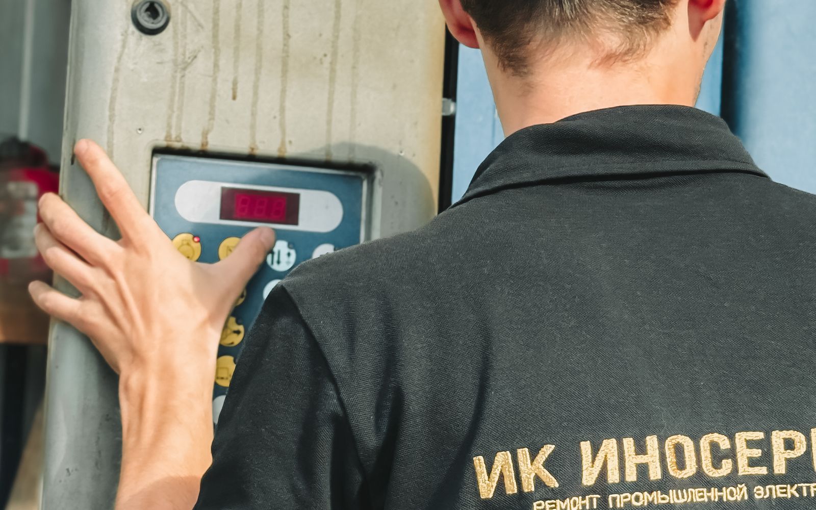 Industrial technician inspecting a control panel representing operational-technology security environments.