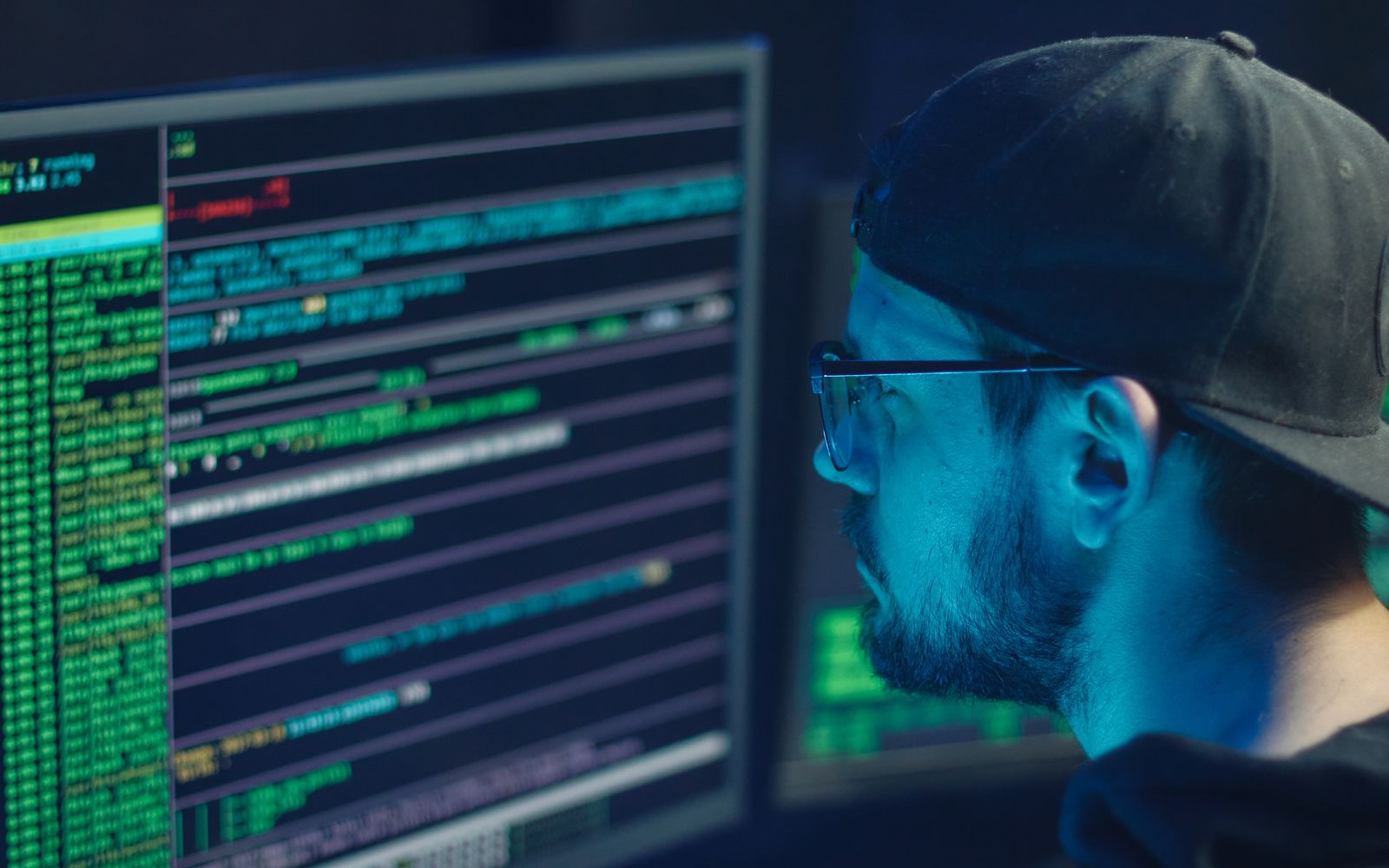 Cybersecurity professional reviewing technical data across multiple monitors for detection and investigation.